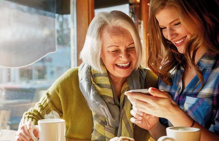 Woman showing her phone to an older woman over coffee, cosmetic bonding in Pryor OK