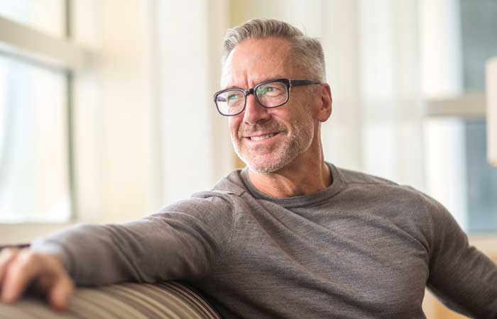 Man smiling on a couch, dental implants in Pryor, OK