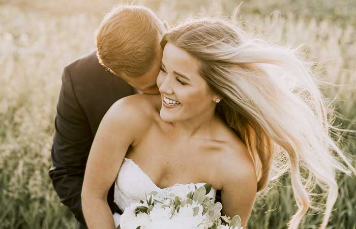 Bride and groom embracing in a field, smile whitening in Pryor, OK